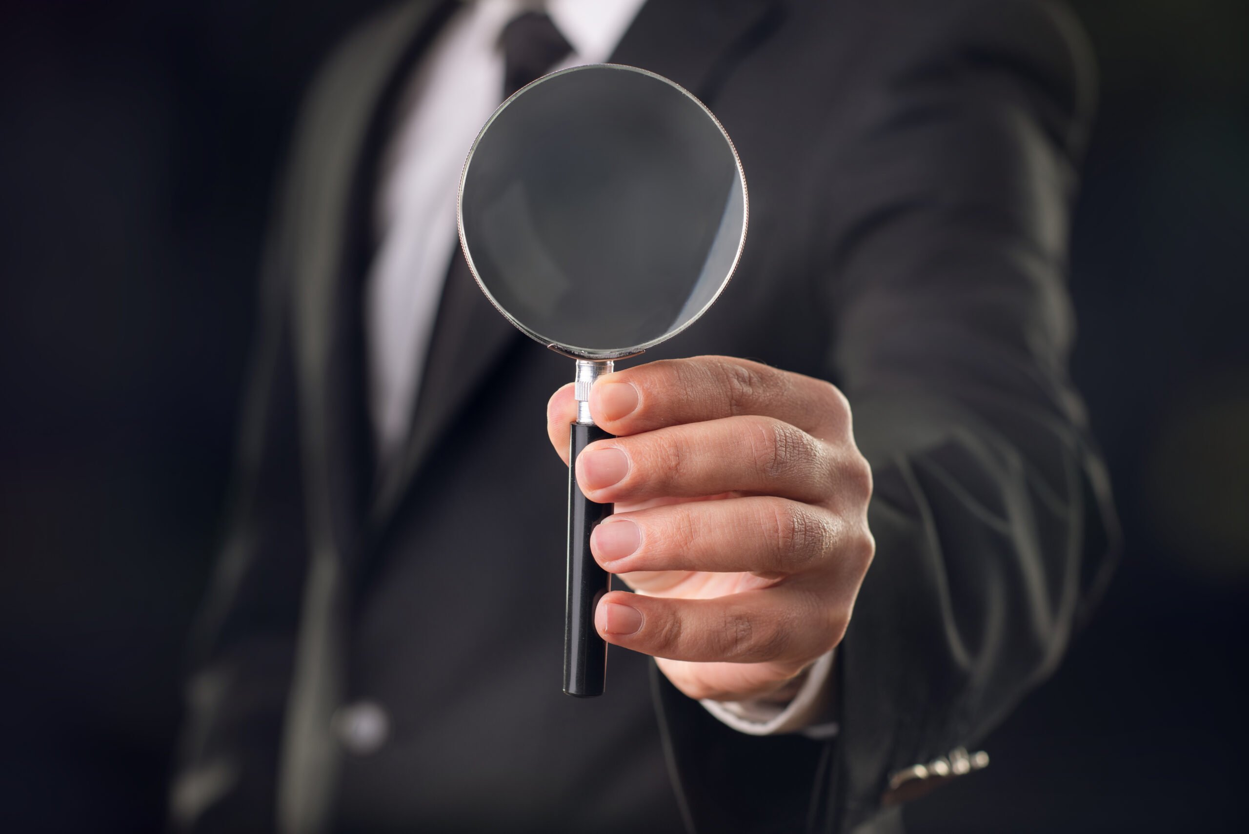 businessman with magnifying glass on dark background