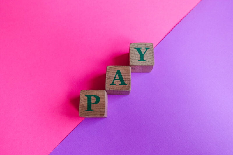 pay, wood blocks on pink and lilac background.