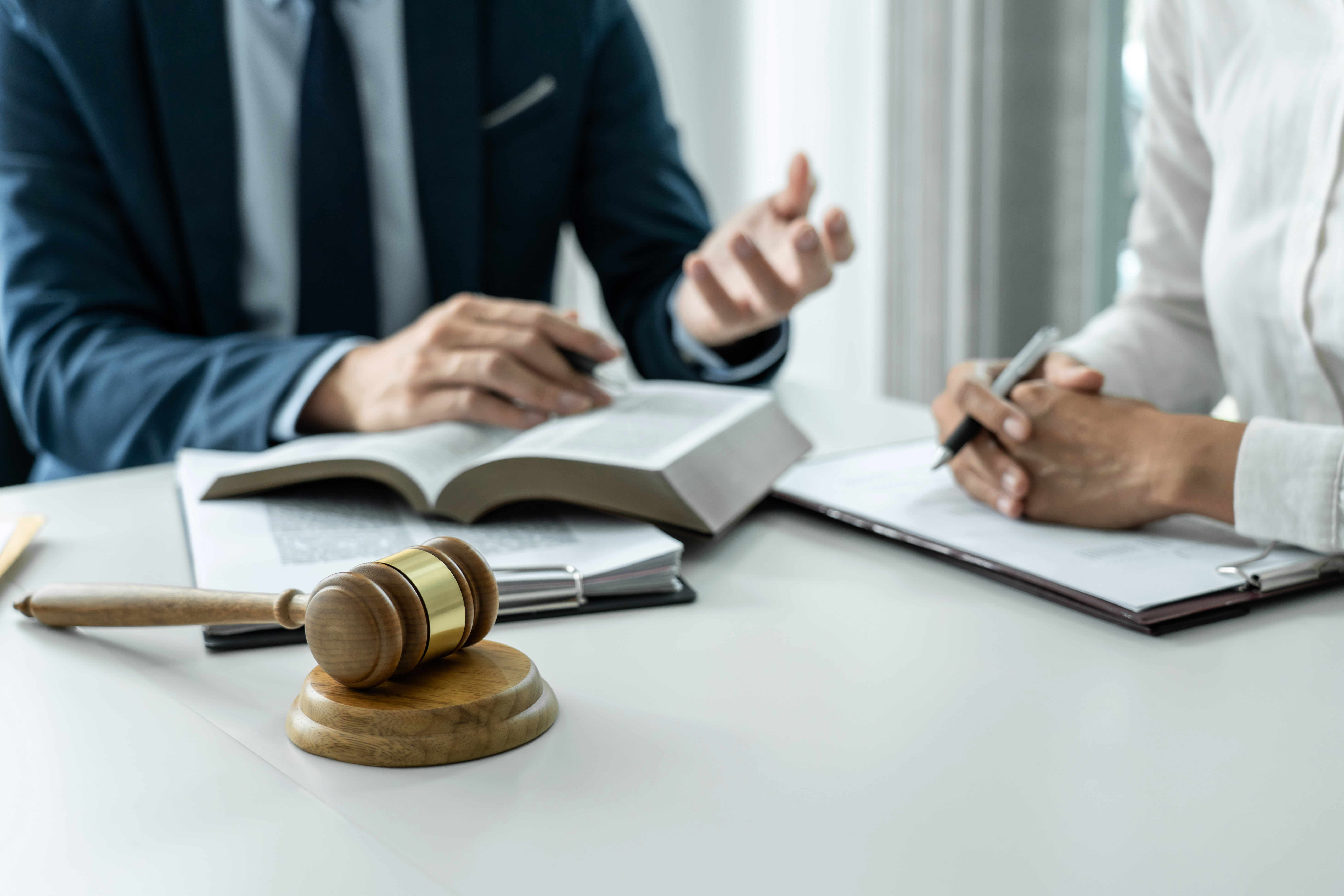 male lawyer and professional businesswoman working and discussion having at law firm in office, judge gavel with scales of justice